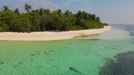 Drohnenflug-über-Die-Maledivische-Küste-Mit-Vielen-Grünen-Bäumen,-Blick-Vom-Meer-Vor-Dem-Hintergrund-Eines-Stürmischen-Himmels