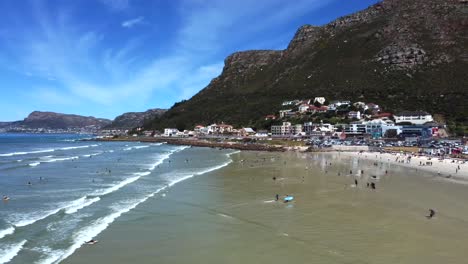 Side-drone-shot-of-surfers-at-Muizenberg-beach,-Cape-Town---docents-of-surfers-in-the-water