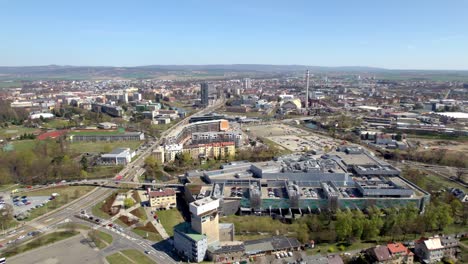 Panorama-of-the-city-of-Olomouc-with-passing-cars-and-public-transport-around-the-Å antovka-department-store,-Czech-Republic---aerial-view