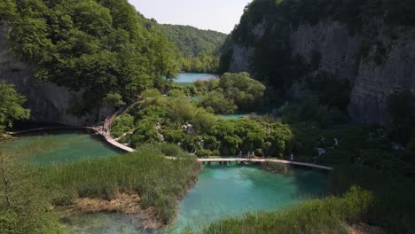Blick-Von-Oben-Auf-Den-Nationalpark-Plitvicer-Seen-Mit-Grünen-Pflanzen-Und-Wunderschönen-Seen-Und-Wasserfällen,-Zwischen-Denen-Menschen-Hingehen