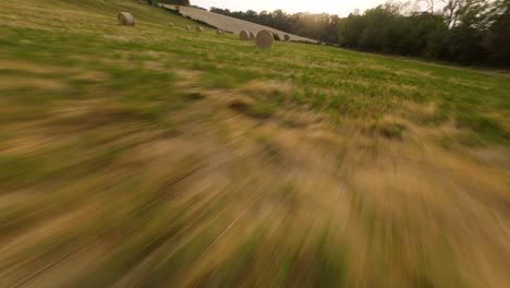 Flying-leftwards-in-a-hay-bales-field-with-an-FPV-drone-at-sunset