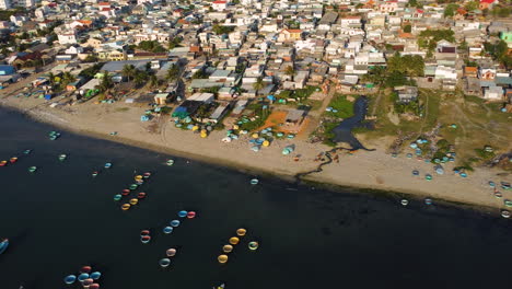 Aerial-panorama-of-beach-in-Mui-Ne-town,-Vietnam-with-many-colorful-coracle-boats