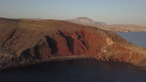 Afternoon-aerial-view-of-iconic-red-beach-cliffs-on-coast-of-Santorini