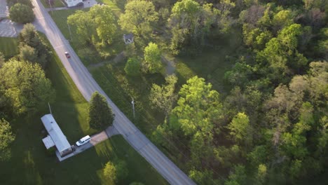 Late-afternoon-birds-eye-view-over-small-town-road-with-trees-and-cars