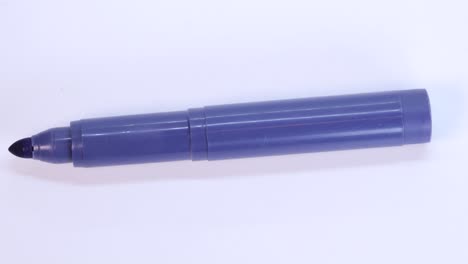 Purple-marker-pen-rotating-on-white-surface-background,-macro-shot-close-up-view-detail