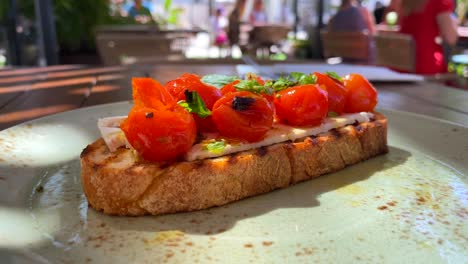 Delicious-bruschetta-sourdough-toast-with-cherry-tomatoes-and-basil,-traditional-italian-breakfast-brunch-dish-at-a-restaurant,-4K-shot