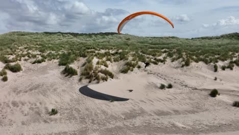 Extreme-paragliding-over-sandy-beach,-aerial-drone-view