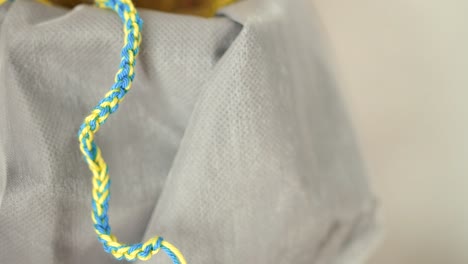 Nahaufnahme-Eines-Selbstgemachten-Armbandes,-Das-Zur-Unterstützung-Des-Ukrainischen-Volkes-Hängt,-Indem-Ein-Armband-In-Den-Farben-Der-Ukrainischen-Flagge-Wie-Gelb-Und-Blau-Hergestellt-Wird