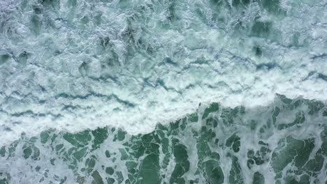 Top-down-shot-of-waves-on-the-west-coast-crashing-in-slow-motion