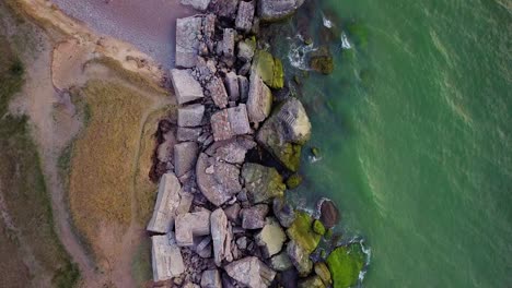 Aerial-birdseye-view-of-abandoned-seaside-fortification-buildings-at-Karosta-Northern-Forts-on-the-beach-of-Baltic-sea-in-Liepaja,-Latvia,-calm-sea,-wide-drone-shot-moving-forward