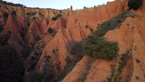 Aerial-drone-flight-over-Las-Cárcavas-de-la-Sierra-de-Ayllón,-in-Madrid-during-sunny-day---Growing-plants-and-bush-on-sandstone-hills