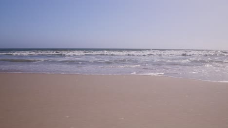 Low-Level-Schwenkaufnahme-Aus-Sandperspektive,-Die-Wellen-Zeigt,-Die-An-Die-Küste-In-Santa-Monica,-Ca