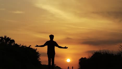Kostenlose-Silhouette-Eines-Mannes,-Der-Auf-Der-Straße-Zwischen-Den-Bergen,-Wolken,-Hintergrundbeleuchtung-Bei-Sonnenuntergang-In-Der-Stadt-Diu-In-Indien-Läuft