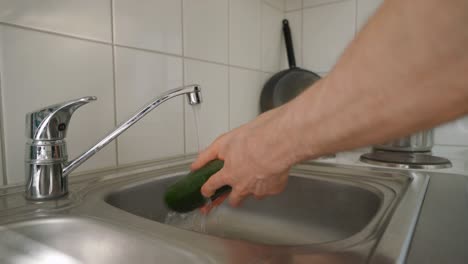 Man-washing-a-zucchini-under-running-water.-Cooking