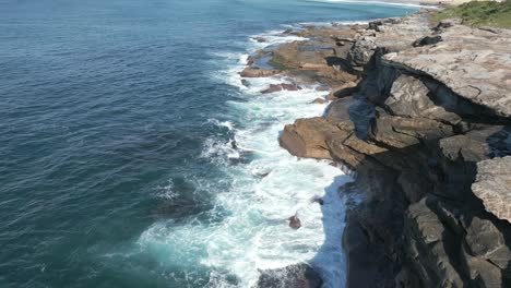 Aerial-view-of-ocean-waves-crashing-the-rocks-at-Sydney-Coastline