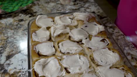 Spreading-cream-cheese-frosting-on-homemade-cinnamon-rolls---isolated-dynamic-motion