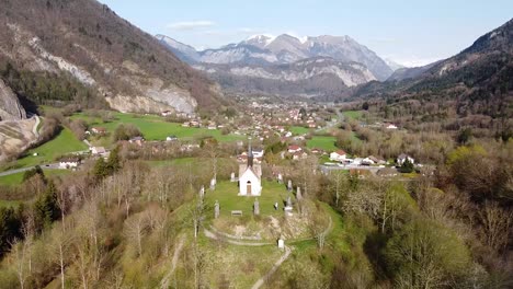 Drone-Shot-of-a-Chapel-on-top-of-a-Hill-in-front-of-Alpine-Mountains
