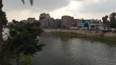 Vista-Panorámica-Del-Río-Nilo-En-El-Cairo-Con-Edificios-Residenciales-En-La-Orilla-Del-Río,-Cielo-Nublado