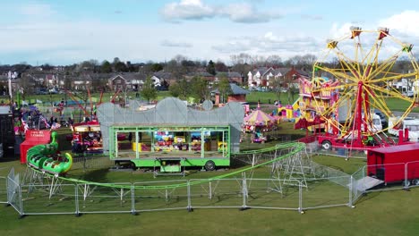 Small-town-family-fairground-Easter-holidays-colourful-funfair-rides-in-public-park-aerial-view