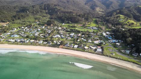 Aerial-view-of-small-surf-town-in-New-Zealand's-North-island
