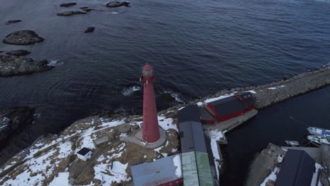 Aerial-downward-view-orbitting-the-Andenes-Lighthouse-with-people-on-top,-and-snow-on-the-ground