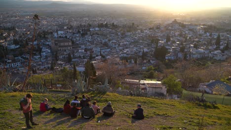 Group-of-friends-on-top-of-hill-watching-beautiful-sunset-over-city-below