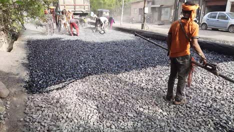 A-Closeup-Video-Shot-Of-Workers-Arranging-Asphalt-Road-Or-Damar-Road-Constructions---worker-spraying-asphalt-on-the-city-road-in-India