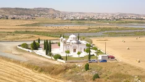 Drone-Flying-Towards-Beautiful-White-Church-With-Stunning-Lake-Background,-Larnaca-City,-Cyprus
