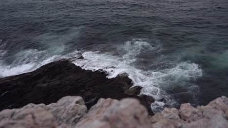 Wellen-Des-Atlantischen-Ozeans,-Die-Entlang-Der-Europäischen-Küste-Gegen-Felsen-Spülen-–-Statischer-Abendclip-Mit-Blick-Auf-Das-Meer-Nach-Sonnenuntergang-Mit-Heller-Klippe-Im-Vordergrund,-Nah-An-Der-Kamera