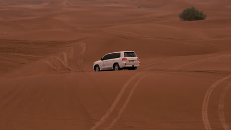 Car-drives-over-the-dunes-in-the-dessert-near-Dubai,-UAE
