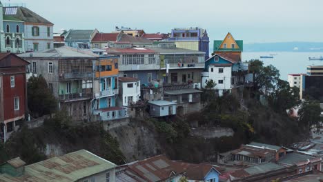 Jib-up-of-picturesque-colorful-hillside-houses-in-Cerro-Alegre,-sea-in-background-on-an-overcast-day,-Valparaiso,-Chile