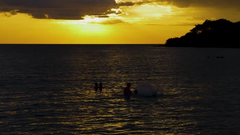 Silhouettes-of-family-playing-in-the-sea-at-dusk