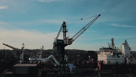 Drone-flying-around-crane-while-loading-cargo-ship-in-docks
