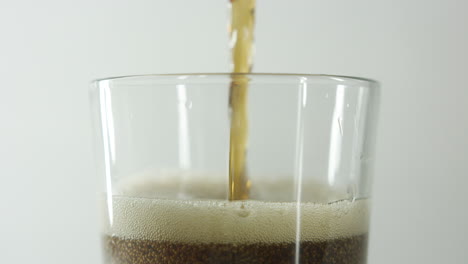 close-up-in-slow-motion-of-the-top-of-a-glass-being-filled-with-cola-drink-against-a-clear-light-background