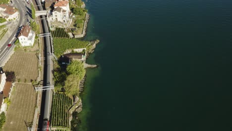 Aerial-top-down-view-of-Swiss-train-passing-along-the-shore-of-Lake-Léman-in-Lavaux-vineyard