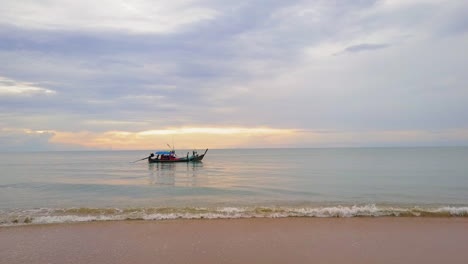 Sunset-seen-from-the-beach-with-a-long-tail-boat-on-the-water