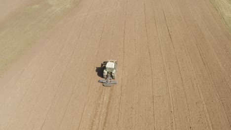 Drone-shot-following-tractor-preparing-field-for-sowing-Near-Mont-Pèlerin,-Vaud,-Switzerland