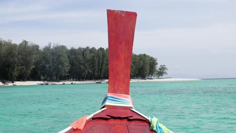Ultra-Zeitlupenaufnahme-Der-Roten-Vorderseite-Eines-Longtail-Bootes,-Das-Sich-Dem-Atemberaubenden-Strand-Einer-Insel-In-Thailand-Nähert