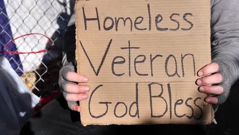 Homeless-veteran-being-interviewed-and-talking-with-his-hands-while-holding-sign-saying,-"Homeless-veteran,-God-bless"