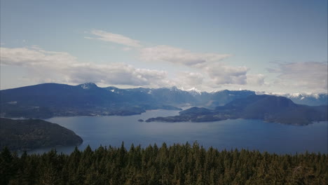Aerial-revealing-shot-of-forest-and-Canadian-Mountains-surrounded-Ocean