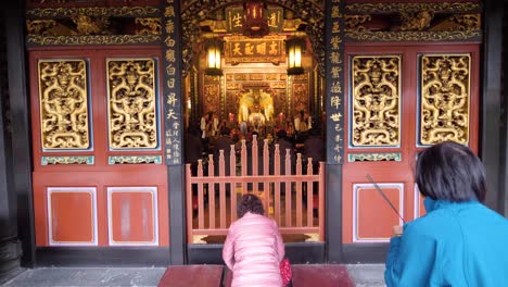 Slow-motion-shot-of-woman-praying-and-bowing-at-Dalongdong-Baoan-Temple-in-Taipei,-Taiwan