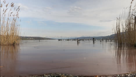 Time-lapse-shot-overlooking-Lake-Hallwyl-with-snowy-mountains-in-the-background