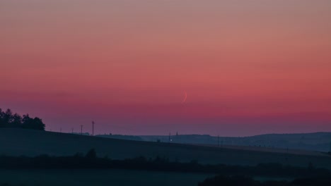Crescent-moon-set-time-lapse-with-orange-sky-and-short-fireworks-on-the-horizon,-less-surroundings