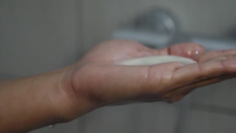 Close-up-of-a-woman's-hand-as-she-squirts-shampoo-into-her-hand-during-a-shower