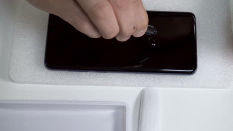 Mann-Gießt-Flüssigen-Kleber-Vorsichtig-Auf-Den-Smartphone-Bildschirm