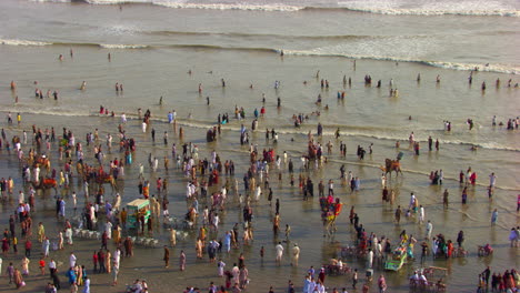 Luftaufnahme-über-Den-Strand-Mit-Meerblick-In-Karachi,-Pakistan,-Hunderte-Von-Menschen-Sind-Zusammen,-Um-Die-Wunderschönen-Sonnenstrahlen-Auf-Den-Wellen-Des-Meeres-Zu-Genießen