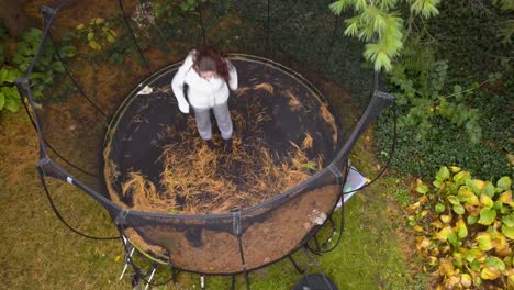 Lowering-drone-shot-over-a-teenaged-girl-jumping-on-a-trampoline-in-the-fall