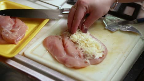 Adding-shredded-cheese-on-top-of-the-pre-cut-raw-chicken-breast-piece