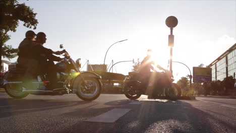 Silhouettes-of-heavy-motorbikes-crossing-a-big-street-at-sunset,-frontlighting