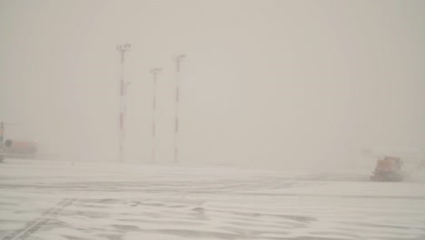 Orangefarbene-Schneepflüge-Reinigen-Den-Landeweg-Des-Flughafens-An-Einem-Nebligen,-Verschneiten-Tag-Vom-Schnee